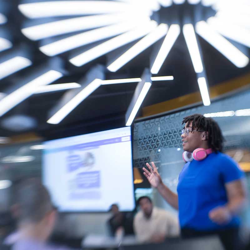a student gives an energetic presentation to a light-filled classroom